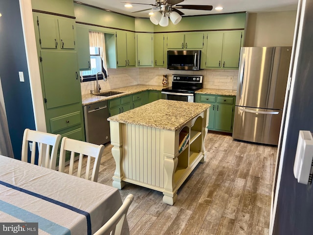 kitchen with a sink, green cabinetry, appliances with stainless steel finishes, and decorative backsplash