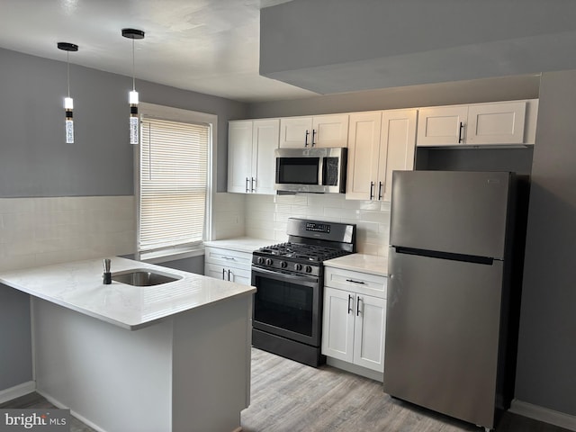 kitchen featuring white cabinetry, a peninsula, a sink, and stainless steel appliances