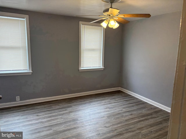 empty room with dark wood finished floors, a ceiling fan, baseboards, and a wealth of natural light