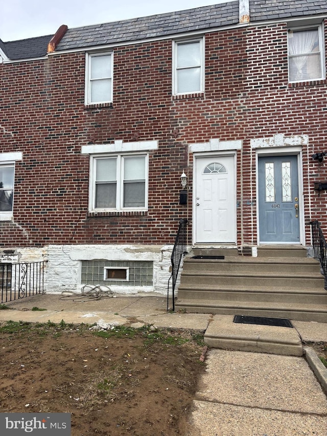 view of front of house with a high end roof, mansard roof, and brick siding