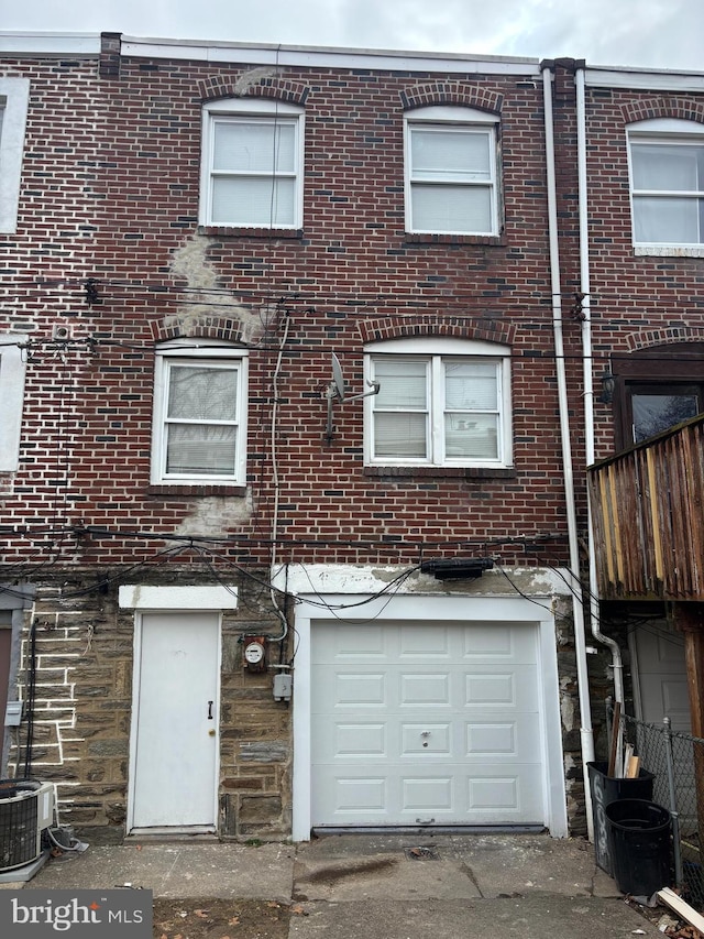 view of front of home with a garage, brick siding, and central AC unit