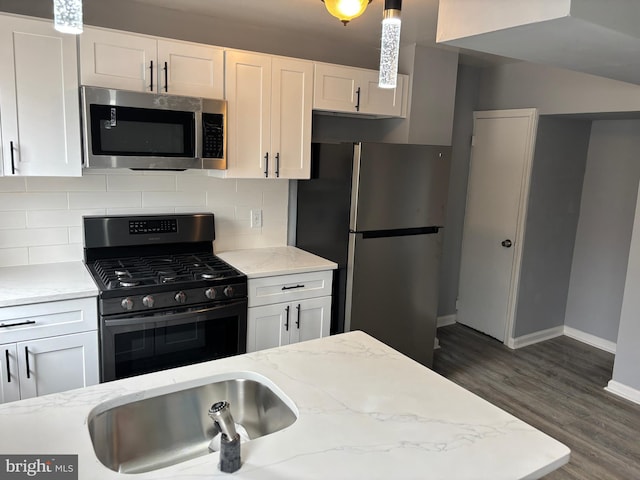 kitchen with dark wood-type flooring, backsplash, appliances with stainless steel finishes, white cabinets, and light stone countertops