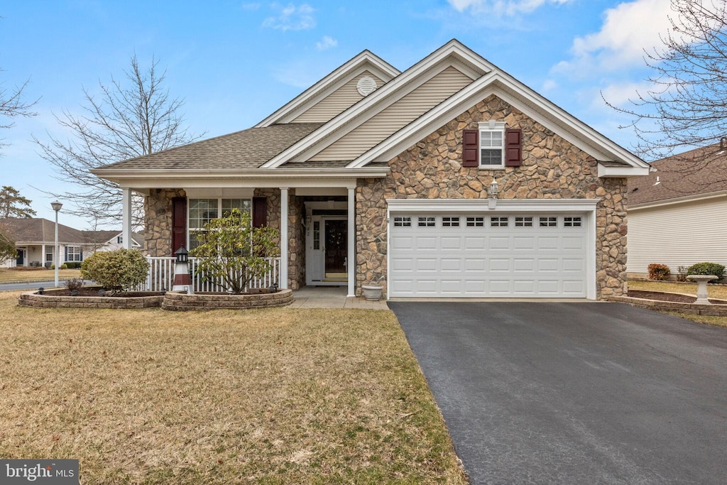 view of front of property with a garage, stone siding, a front yard, and driveway