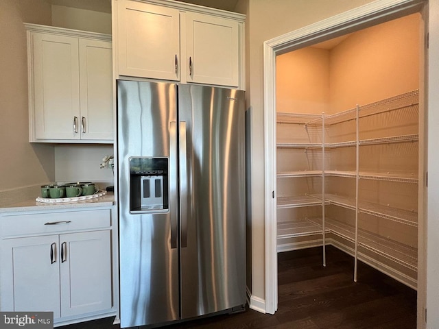 kitchen featuring light countertops, dark wood finished floors, stainless steel refrigerator with ice dispenser, and white cabinetry