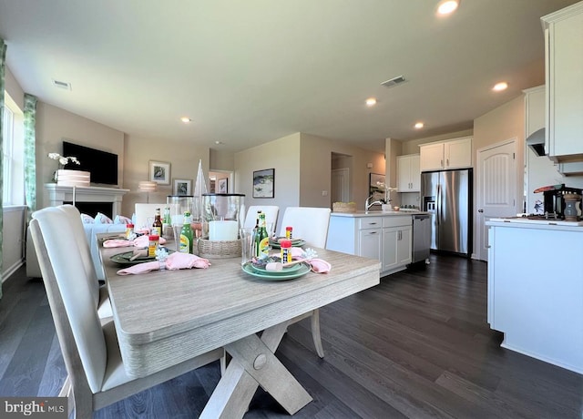 dining space featuring a fireplace, recessed lighting, dark wood-style floors, and visible vents