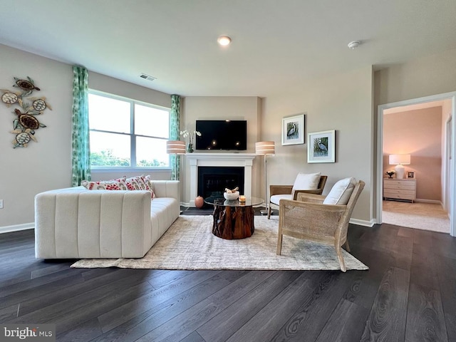 living area featuring dark wood-style floors, visible vents, a fireplace, and baseboards