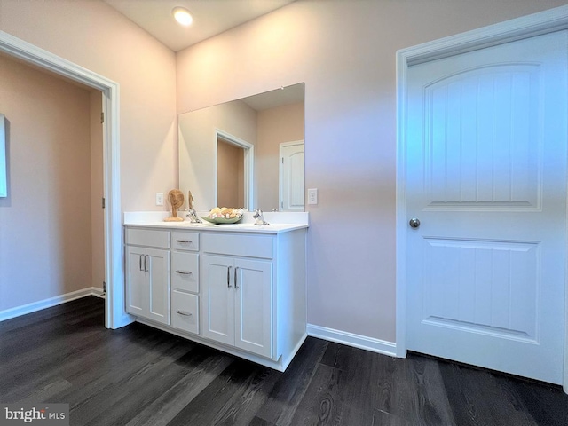 bathroom with double vanity, a sink, baseboards, and wood finished floors