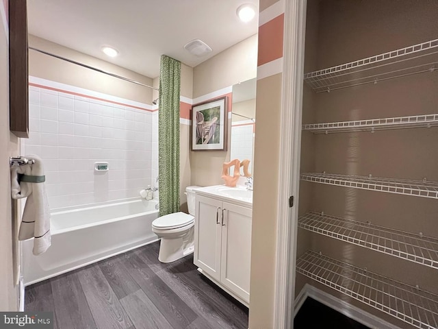 bathroom with vanity, wood finished floors, visible vents, shower / bath combo with shower curtain, and toilet