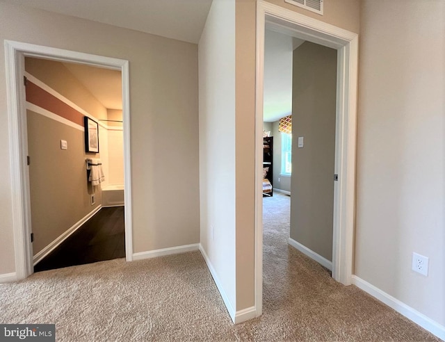 corridor featuring baseboards and carpet floors