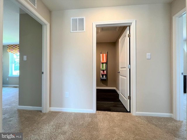 hall featuring baseboards, visible vents, and dark carpet