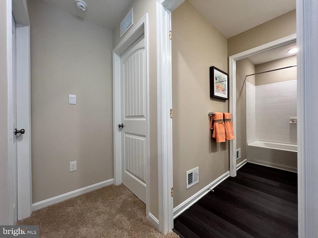 hallway with visible vents, baseboards, and dark colored carpet