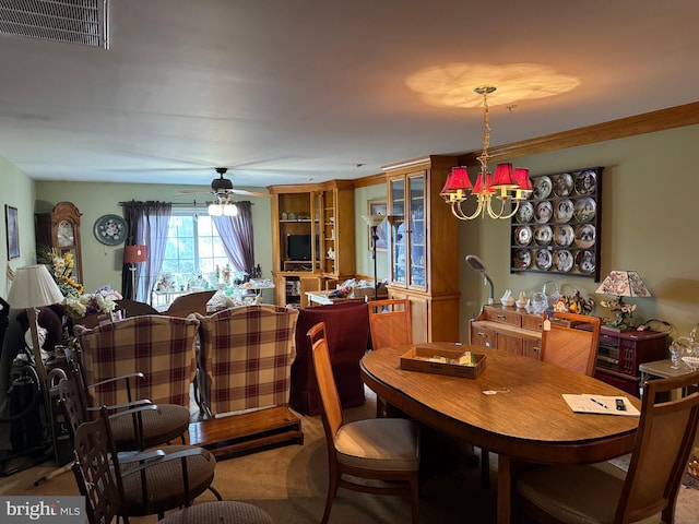 carpeted dining room with crown molding, ceiling fan with notable chandelier, and visible vents