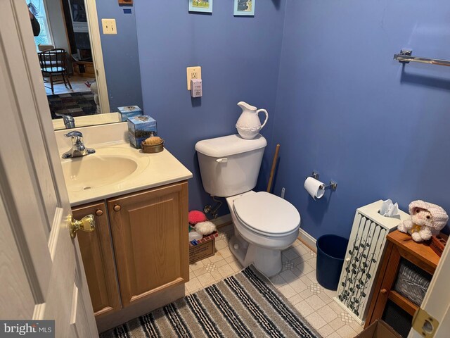 half bath with toilet, vanity, and baseboards