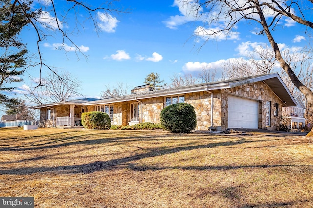 view of front of home featuring a porch, stone siding, an attached garage, and a front yard