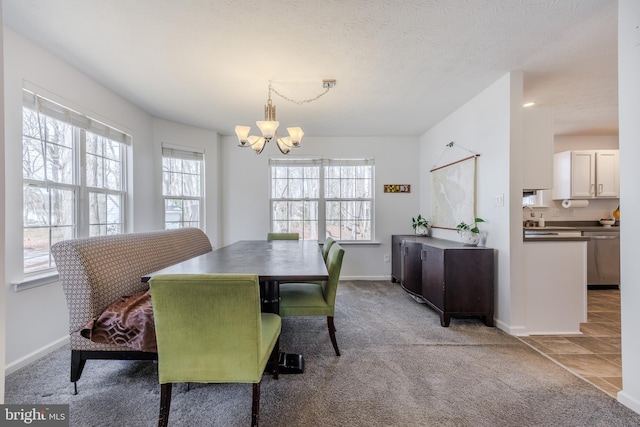 carpeted dining area with a textured ceiling, an inviting chandelier, baseboards, and a sink