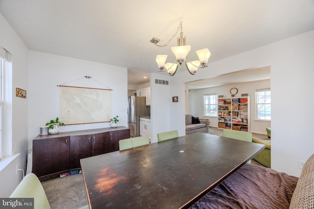 carpeted dining room with a notable chandelier and visible vents