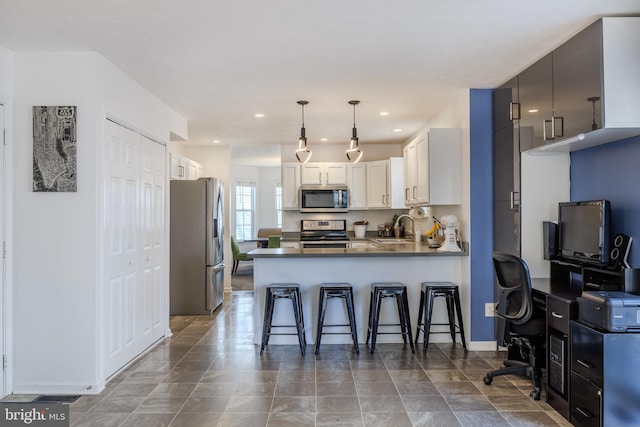 kitchen with a breakfast bar, a sink, stainless steel appliances, a peninsula, and white cabinets