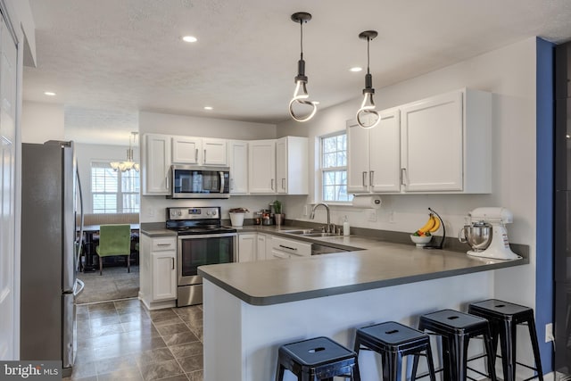 kitchen featuring white cabinetry, a peninsula, stainless steel appliances, and a sink