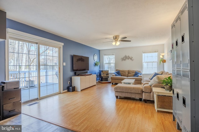 living area featuring visible vents, baseboards, light wood-style floors, and ceiling fan