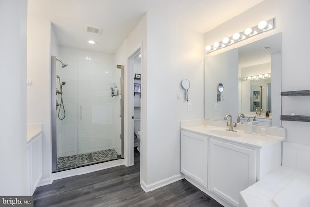 full bath with vanity, wood finished floors, visible vents, a stall shower, and toilet