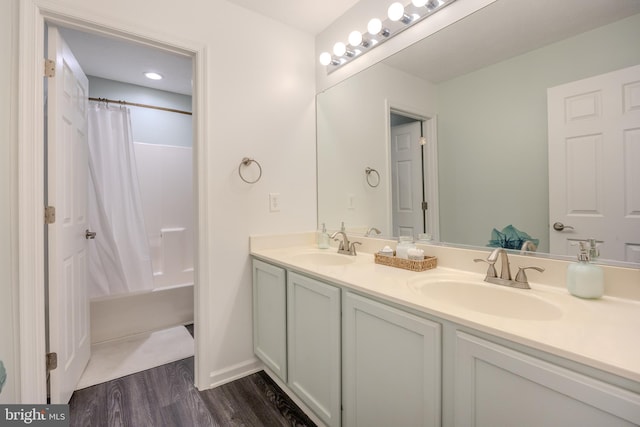 bathroom featuring double vanity, wood finished floors, shower / bath combo with shower curtain, and a sink