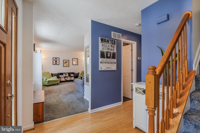 hall featuring visible vents, stairway, baseboards, and light wood-style floors