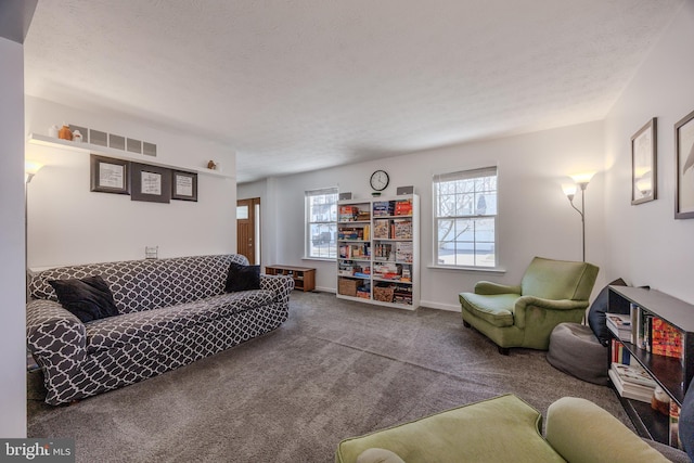 living area with visible vents, baseboards, a textured ceiling, and carpet flooring