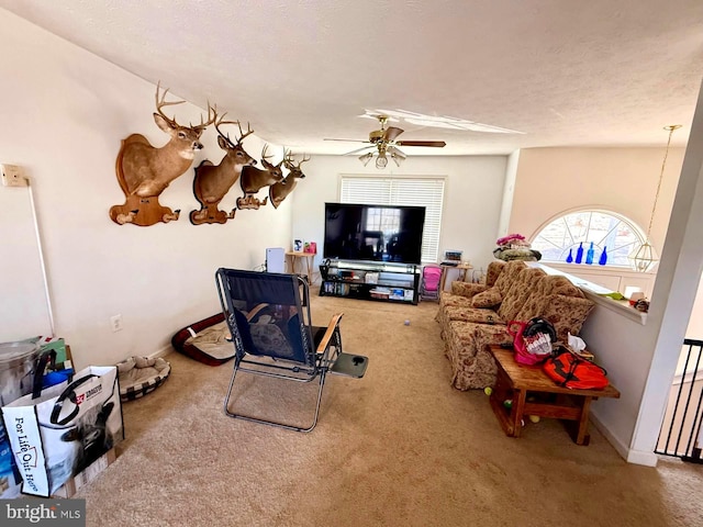 living room with baseboards, a textured ceiling, carpet, and a ceiling fan