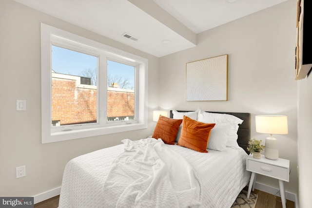 bedroom with visible vents, baseboards, and wood finished floors