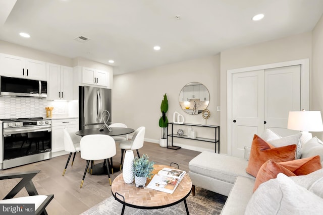 living area featuring recessed lighting, visible vents, baseboards, and light wood-style floors