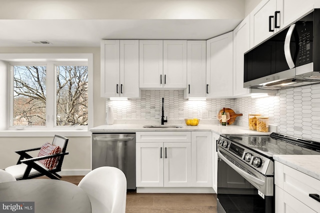 kitchen with tasteful backsplash, visible vents, appliances with stainless steel finishes, white cabinetry, and a sink