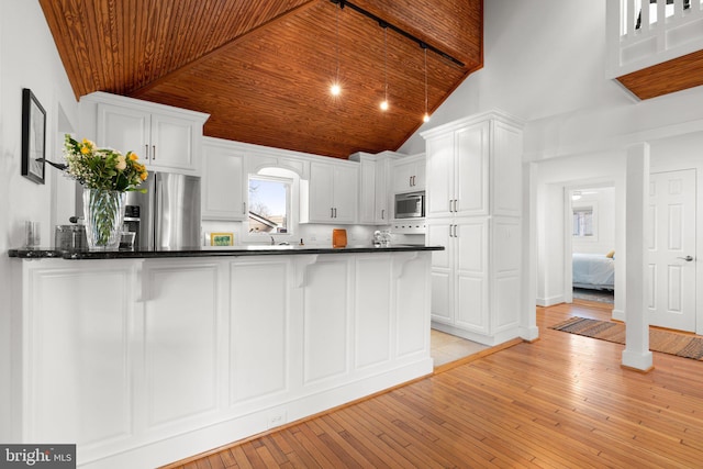 kitchen with dark countertops, light wood-style floors, appliances with stainless steel finishes, wooden ceiling, and white cabinets