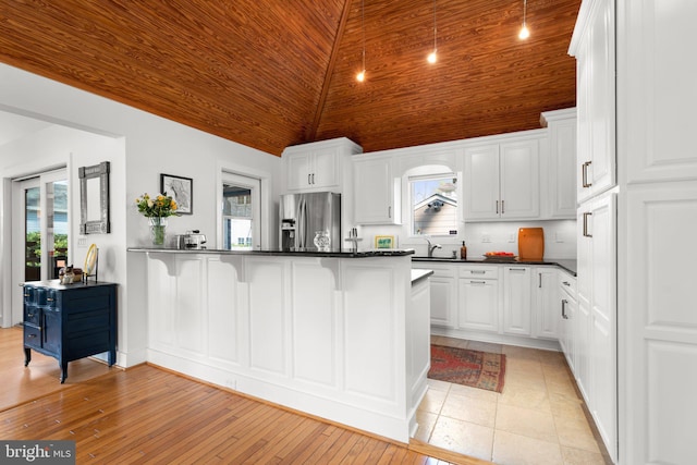 kitchen featuring a breakfast bar, dark countertops, wood ceiling, and stainless steel refrigerator with ice dispenser