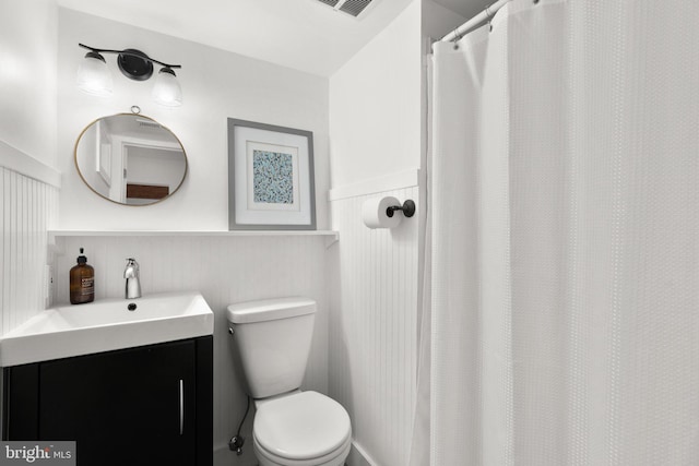 full bathroom with wainscoting, toilet, and vanity