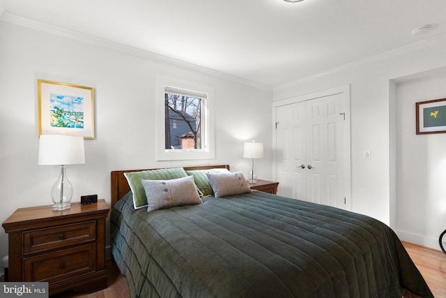 bedroom featuring a closet, baseboards, wood finished floors, and ornamental molding