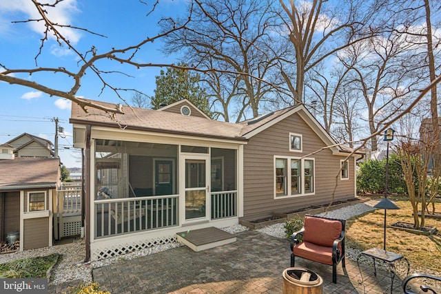 back of house with a patio, an outdoor fire pit, a shingled roof, and a sunroom