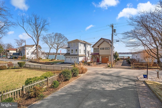 view of front facade featuring a fenced front yard, driveway, a front lawn, and a garage