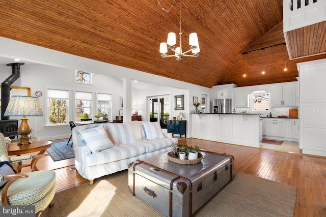 living area featuring light wood finished floors, wood ceiling, high vaulted ceiling, and a wood stove