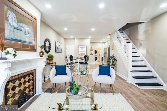 living area with stairs, recessed lighting, wood finished floors, and a fireplace