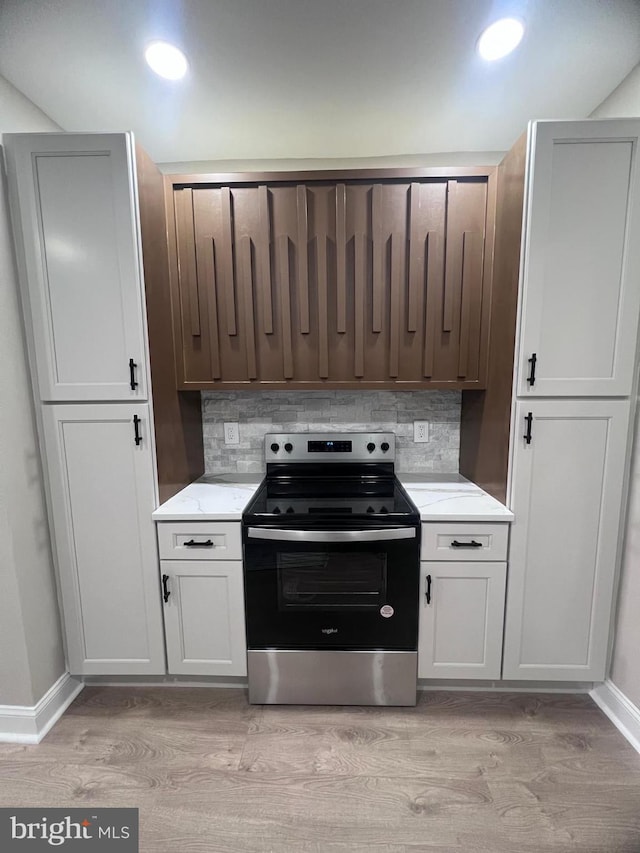 kitchen featuring light stone counters, stainless steel range with electric cooktop, tasteful backsplash, and light wood-type flooring