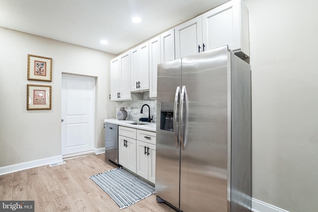 kitchen featuring white cabinets, light wood-type flooring, appliances with stainless steel finishes, and a sink