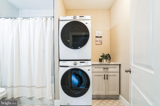 clothes washing area with stacked washer / drying machine, baseboards, and laundry area