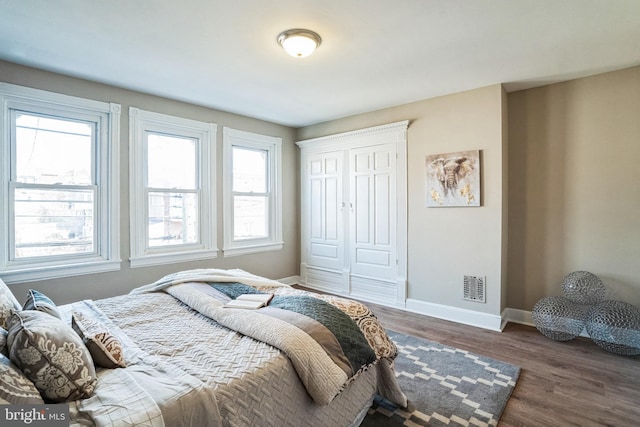 bedroom featuring a closet, visible vents, baseboards, and wood finished floors