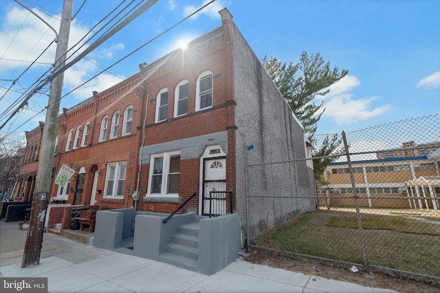 view of front facade with a front yard, fence, and brick siding