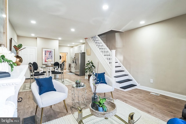 living room featuring light wood finished floors, visible vents, recessed lighting, and stairway