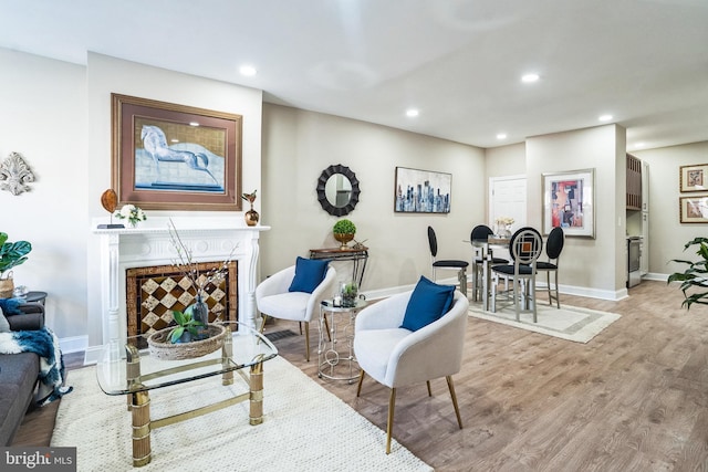 living room featuring a tiled fireplace, recessed lighting, baseboards, and wood finished floors