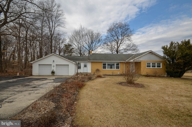 ranch-style house featuring brick siding, a front lawn, a chimney, a garage, and driveway