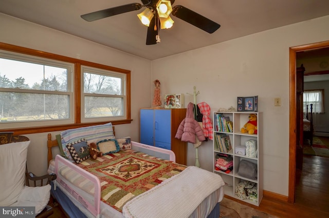 bedroom featuring a ceiling fan, wood finished floors, baseboards, and a baseboard radiator