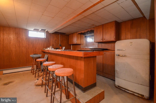 bar featuring a baseboard radiator, indoor bar, concrete floors, and wood walls