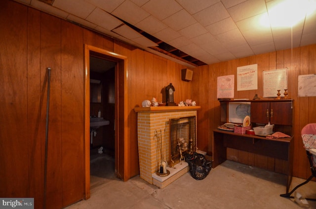 interior space featuring a brick fireplace, concrete floors, and wood walls